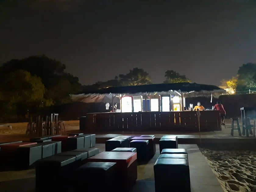 La barra de CostaMansa iluminada de noche, con livings sobre la arena