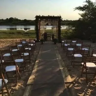 Sillas de madera y arco de ceremonia sobre la arena, mirando al río Paraguay