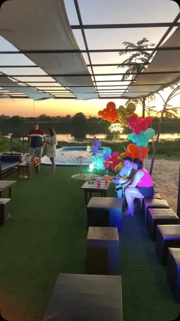 Sector techado con luces y livings montado para un cumpleaños, con el río atrás