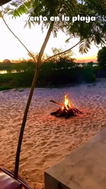Fogata encendida sobre la arena al caer la noche