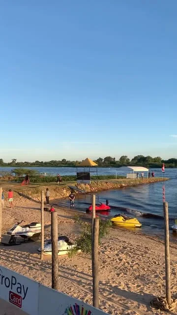 La playa de CostaMansa de día, con motos de agua y sombrillas